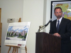 Michael Markman, , president of Horsham-based BET Investments, stands beside an artist's rendering of an apartment building.